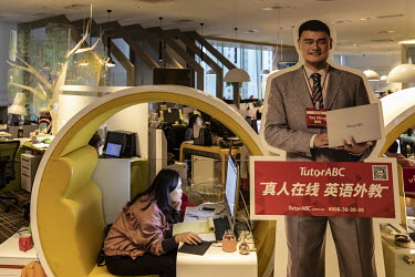 An employee works in a private booth in an iTutorGroup office beside a cutout of Former Chinese basketball star Yao Ming. After seeing raid growth and investment, China's online tutoring sector has al...