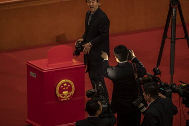 Official photographers and cameramen surround a ballot box during a voting session at the first session of the 13th National People's Congress (NPC) at the Great Hall of the People.