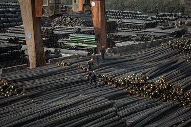 Workers stand on piles of steel rebars at a depot on the outskirts of Shanghai.