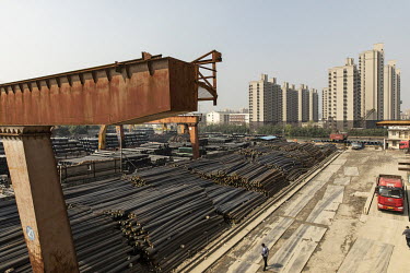 A worker walks past piles of steel rebars at a depot on the outskirts of Shanghai.