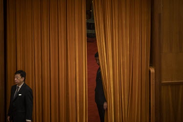 An attendant looks out from behind a curtain at the 13th National People's Congress (NPC) at the Great Hall of the People.