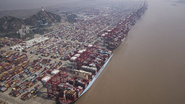 An A.P. Moller-Maersk A/S container ship docked in a terminal beside stacks of containers at the Yangshan Deep Water Port.