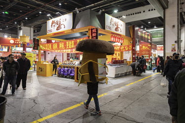 A worker dressed up as a mushroom walks through a Chinese New Year food exhibition.