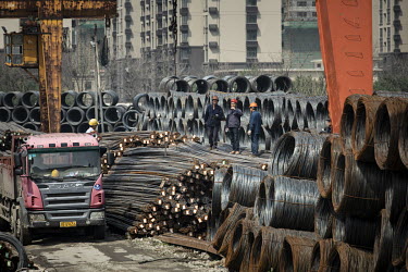 Workers stand on steel rebars next to coils of steel wire at a depot on the outskirts of Shanghai.