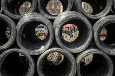 Workers stand on steel rebars next to coils of steel wire at a depot on the outskirts of Shanghai.