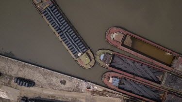 Barges loaded with steel rods and steel wire moored next to a depot.
