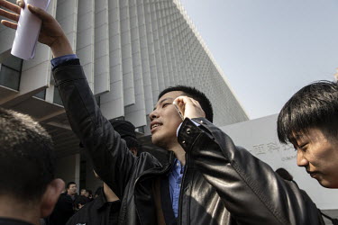 A man waves while talking on his phone outside a Xiaomi Corp smartphone unveiling event. Xiaomi Inc., is a Chinese designer and manufacturer of consumer electronics and related software, home applianc...