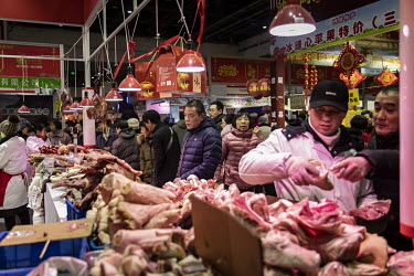 Attendees look at meat products displayed for sale at a Chinese New Year food exhibition.
