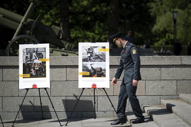 A soldier from Ukraine looks at a display of photographs which make a connection between WW2 and the Russian invasion of Ukraine at the Soviet war memorial in the Tiergarten on 8 May 2022, the 77th an...