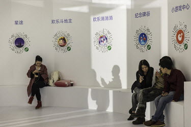 Attendees use their smartphones as QR codes for various in-app games are displayed on a wall at Tencent Holdings Ltd.'s WeChat Open Class Pro conference.