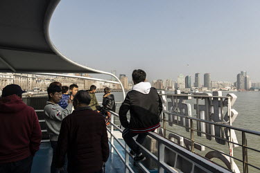 Tourists ride on a ferry crossing the Huangpu River towards the Lujiazui Financial District.