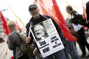 A man carries a Communist Party of Iran flag and a placard featuring the portrait of Karl Marx at a May Day demonstration by various trades unions and left wing political groups.