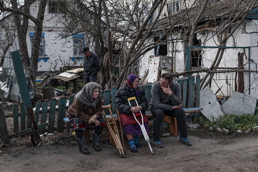 People talking on a bench in Andriivka, a village badly damaged during the Russian invasion.
