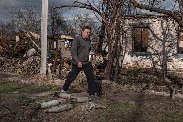 Viktor walks past unexploded projectiles in the remains of the village.