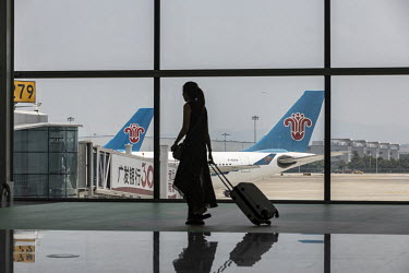 A passenger walks through the departure terminal of the newly opened Terminal 2 of the Guangzhou Baiyun International Airport as China Southern jets sits on the tarmac.