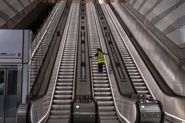 A worker cleans the hand rails on the escalators at the Elizabeth Line's Liverpool Street Station.