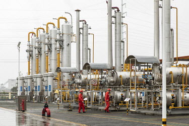 Workers walk amongst pipework and storage tanks stand at a shale gas collection and transfer facility at the Fuling shale gas project site, operated by Sinopec Chongqing Fuling Shale Gas Exploration a...