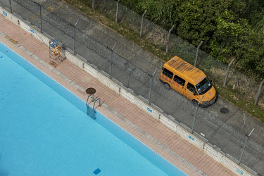 A van moves down an access road alongside a swimming pool and a barbed wire fence near the border with Hong Kong.