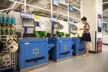 A customer using self-check out tills, paying with a smartphone at a Walmart supermarket.