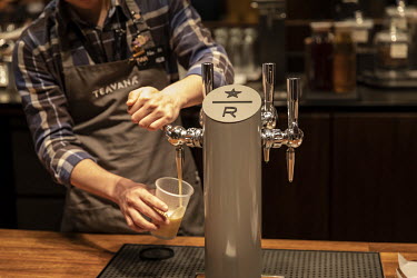 An employee fills up a cup from a tap at the Starbucks Corp. Reserve Roastery store.