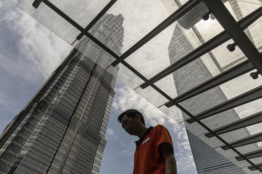 A man walks past the Jin Mao Tower, left, and the Shanghai World Financial Center in Pudong's Lujiazui financial district.