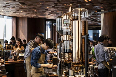 Employees working behind a counter as customers crowd inside the Starbucks Corp. Reserve Roastery store.