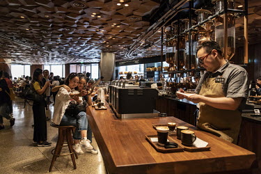 Employees working behind a counter as customers crowd inside the Starbucks Corp. Reserve Roastery store.