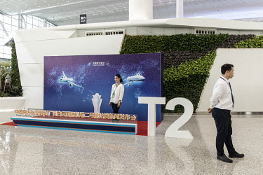 A woman poses for photographs next to a poster commemorating the newly opened Terminal 2 of the Guangzhou Baiyun International Airport.