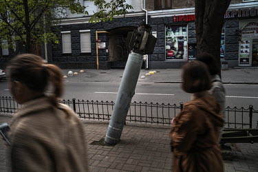 Pedestrians walk past an unexploded Russian rocket on display partly embedded in the pavement of a street in Kyiv.