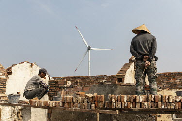 Workers renovate a building near a wind farm operated by China Huaneng Group.