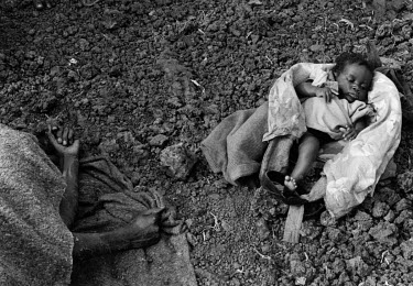A baby lies beside its mother who has died from cholera in the Munigi camp which housed Rwandans fleeing to Zaire (DRC) following the 1994 genocide.