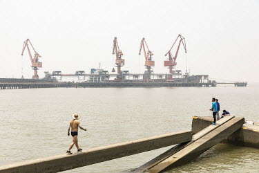 People fishing in the Yangtze River near the Port of Nantong where grain is being unloaded from a bulk transporter and loaded onto smaller river barges at the Nantong Cereals & Oils Transfer Co. facil...