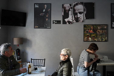 Tourists in a town centre bar where the walls are decorated with images from the film 'The Godfather'.