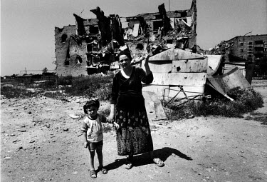 Rosa, a widow, stands with her daughter amidst the ruins of Grozny.