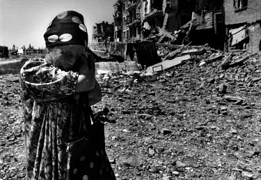 Taus Belashanova, who lost her hands in a rocket attack during the First Chechen war, cries as she stands beside a street of destroyed buildings.