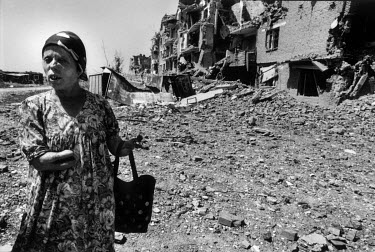 Taus Belashanova, who lost her hands in a rocket attack during the First Chechen war, in front of a bombed out building.