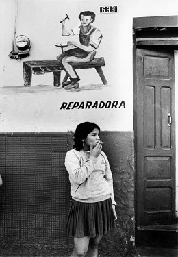 Martine (16) smoking a cigarette outside a cobbler's shop. She decribes being forced into prostitution: "I was sold into a brothel near the U.S. base. We earn't $20 a time from the soldiers, but I nev...