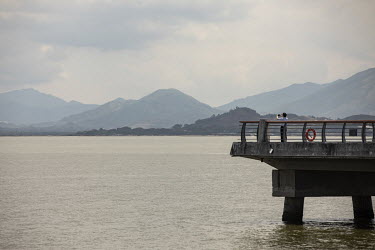 A man takes a picture from the Shenzhen Bay promenade with a view of Hong Kong across the water.