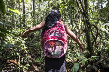 A woman walking through the forest, a daily activity to set up camp for a hunting or fishing trip or to go to school.