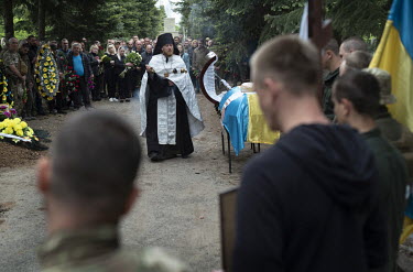An Orthodox priest conducts the service as family and comrades from his regiment mourn at the funeral of Igor Levitzky, a soldier killed in a Russian shelling attack a week ago.