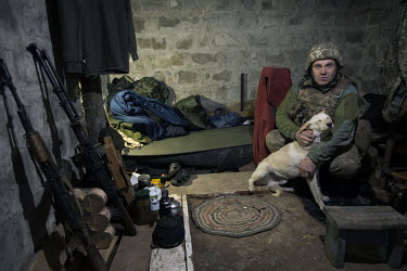 A soldier with a pet dog in a bunker on the Ukrainian front lines facing the Russian held town of Izium.