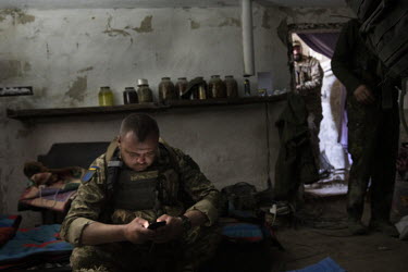 A soldier uses a smartphone in a bunker on the Ukrainian front lines facing the Russian held town of Izium.