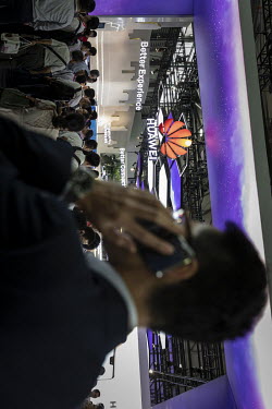 An attendee uses a mobile phone while standing in front of the Huawei Technologies Co. booth at the Mobile World Congress.