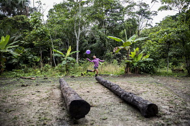 A child plays with a balloon in a village clearing.
