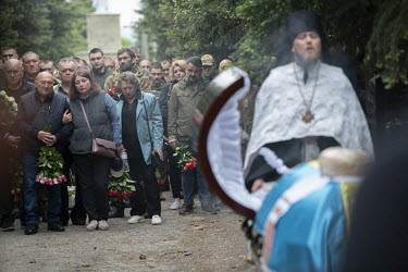 An Orthodox priest conducts the service as family and comrades from his regiment mourn at the funeral of Igor Levitzky, a soldier killed in a Russian shelling attack a week ago.