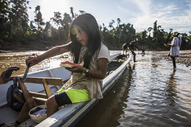 Jade Gualinga eats a water melon snack while sitting in a canoe on the Rio Bobonaza.  Sarayaku has the vision and mission to 'preserve and use in a sustainable way the natural resources of its territo...