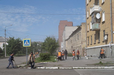 Local residents and volunteers clean up a street in the town after a Russian airstrike.