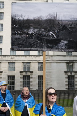 A woman holds up an image of civilians escaping Irpin during a protest, in front of Downing Street, by Ukrainians against Russia's invasion of their homeland.