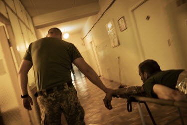 A severely wounded soldier is urgently moved to the operating theatre at a military hospital in an undisclosed location close to the frontline in Donetsk. Most of the soldiers at the facility have bee...