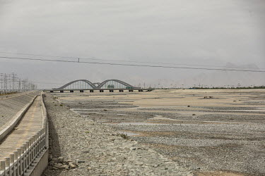 A bridge over a dry river bed with the Gobi desert in the distance.